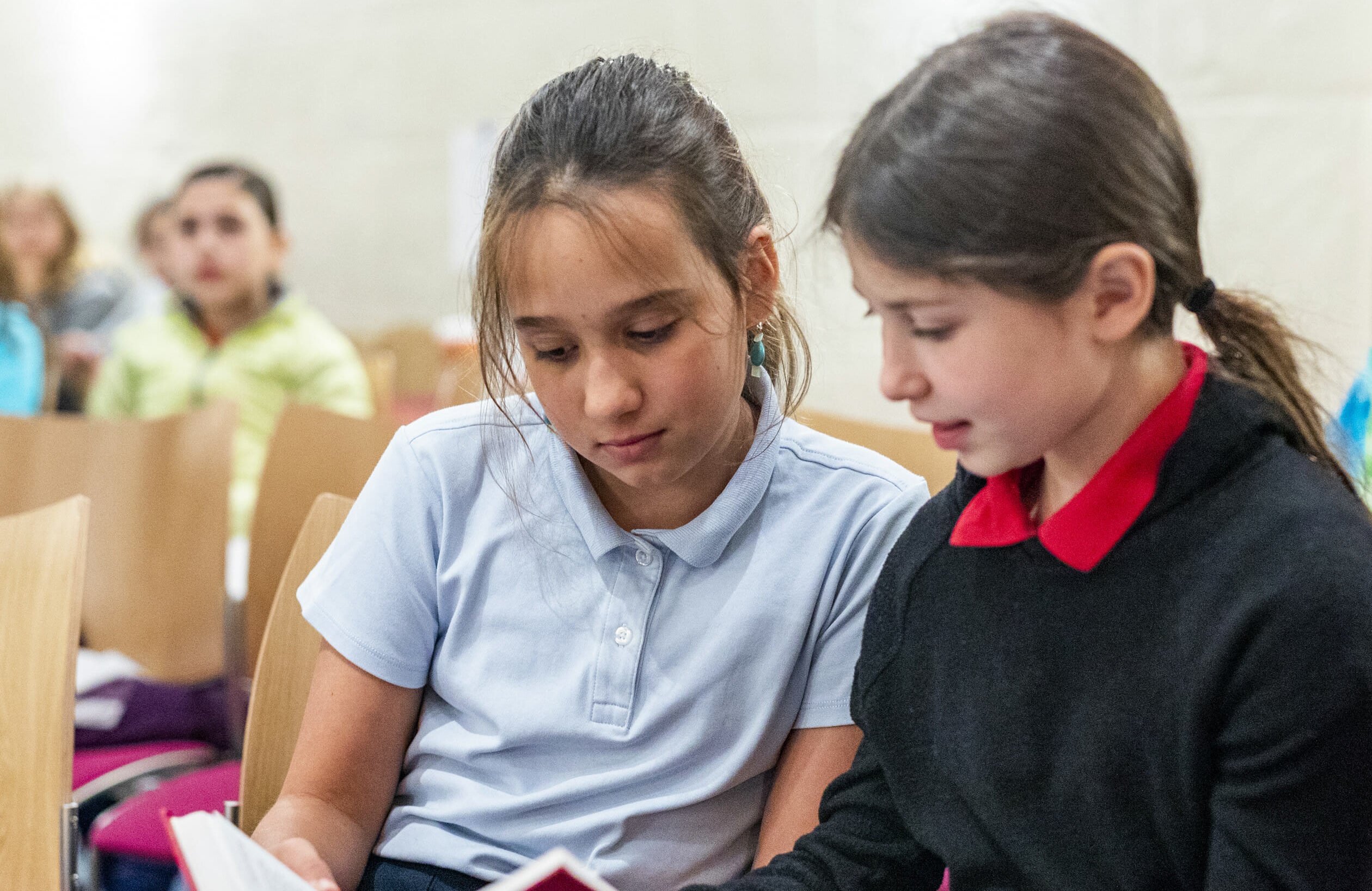 two young girls reading book together